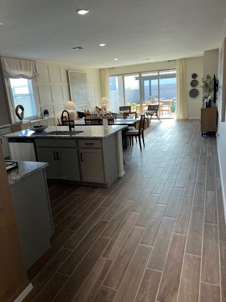 An open-concept kitchen and dining area with sleek wood flooring, modern cabinetry, and large windows overlooking the patio.
