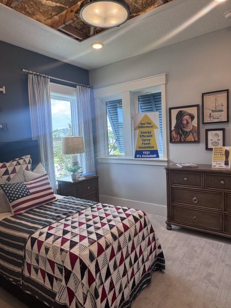 Cozy bedroom with patriotic quilt, rustic dresser, and energy-efficient features, showcasing a blend of style and functionality.