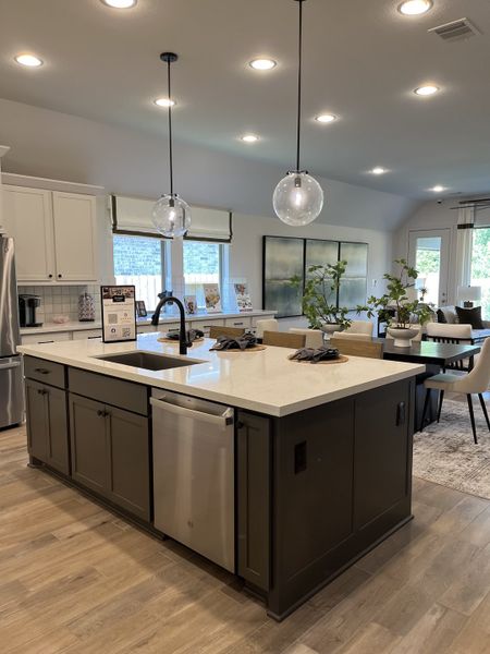 A modern kitchen with a spacious island, sleek cabinetry, and pendant lighting, opening up to a cozy dining area. A modern kitchen with a spacious island, sleek cabinetry, and pendant lighting, opening up to a cozy dining area.