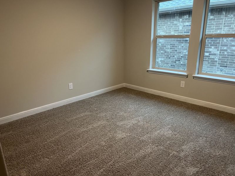 A cozy, carpeted room with neutral walls and two large windows for natural light. A cozy, carpeted room with neutral walls and two large windows for natural light.