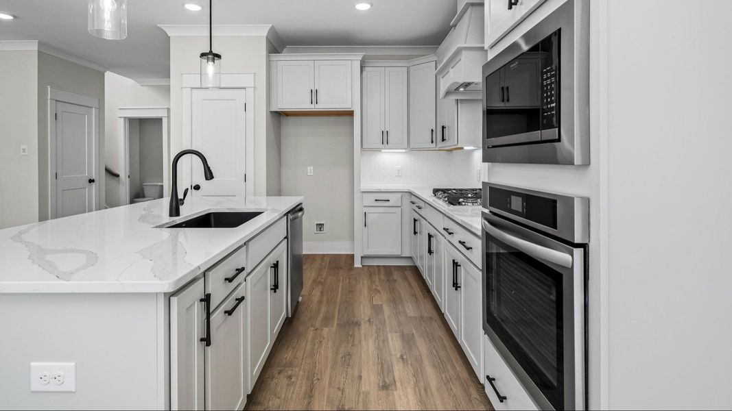 Kitchen with light cabinetry, quartz countertops, and tile backsplash Kitchen with light cabinetry, quartz countertops, and tile backsplash