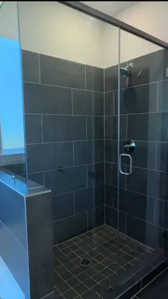 A sleek shower with dark tiles and a glass door, offering a modern and stylish bathroom experience. A sleek shower with dark tiles and a glass door, offering a modern and stylish bathroom experience.