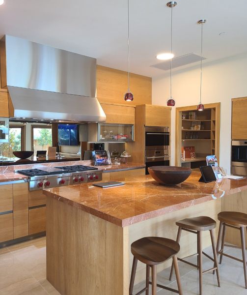 A modern kitchen featuring a marble countertop island, high-end appliances, wood cabinetry, and stylish pendant lights. A modern kitchen featuring a marble countertop island, high-end appliances, wood cabinetry, and stylish pendant lights.