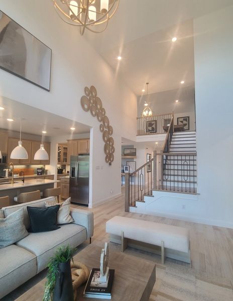 A modern open-concept living area with high ceilings, elegant staircase, and stylish decor.
