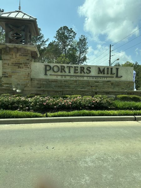 A welcoming stone entrance with lush landscaping at Porters Mill by D.R. Horton in New Caney, TX.