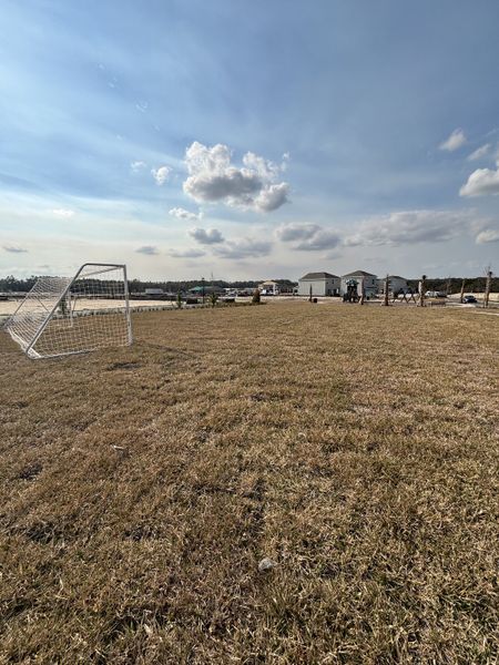 A scenic outdoor space featuring a soccer field and a playground, providing ample recreational opportunities in Crossroads at Kelly Park by Dream Finders Homes (Apopka, FL).