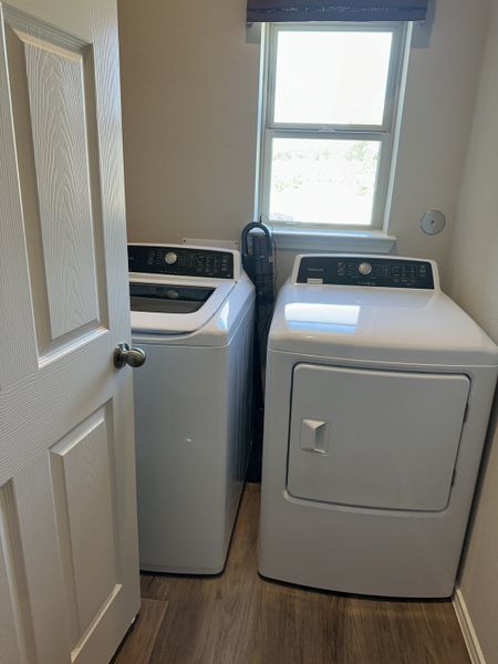 A compact laundry room featuring modern washer and dryer units with natural light from a well-placed window.