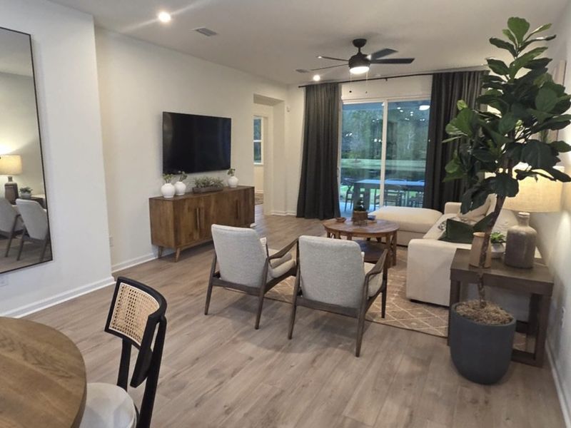 A cozy living room featuring elegant wood floors, modern furnishings, and large windows with lush outdoor views.