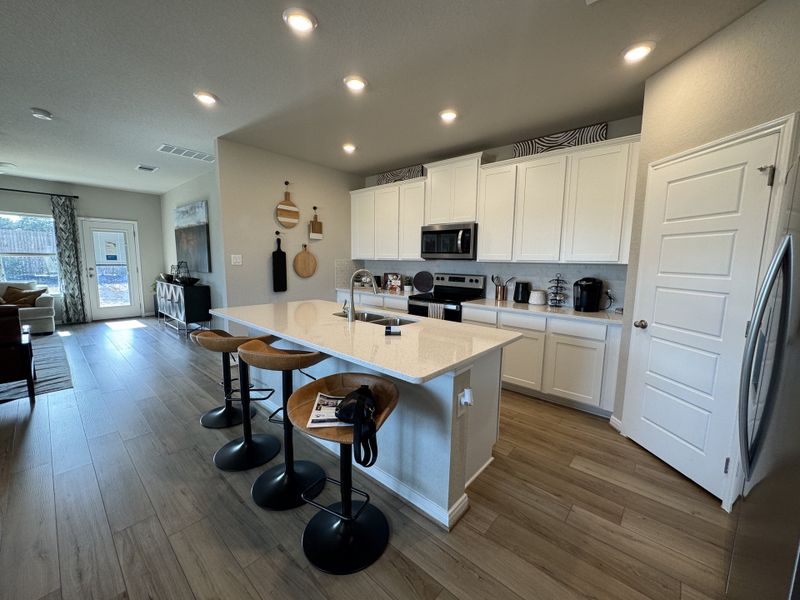 A modern kitchen with white cabinetry, sleek appliances, and a spacious island with bar stools.