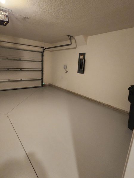 A spacious, clean garage with a smooth concrete floor and overhead door, perfect for parking and storage.
