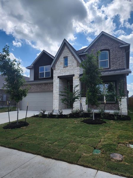 Elegant brick and stone home with lush landscaping in Carillon by Brightland Homes (Manor, TX). Elegant brick and stone home with lush landscaping in Carillon by Brightland Homes (Manor, TX).