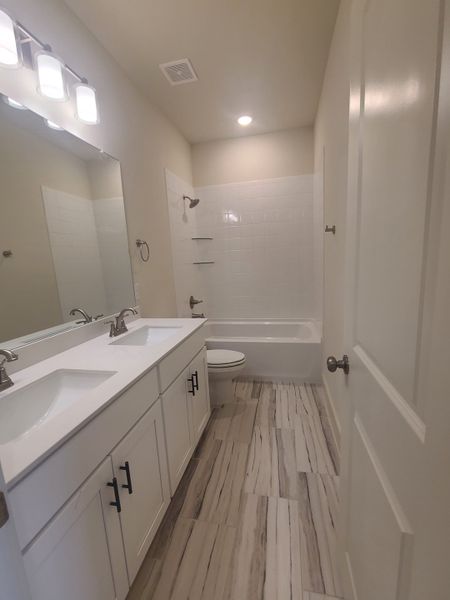 A modern bathroom featuring dual sinks, sleek cabinetry, and a classic bathtub with elegant fixtures and ambient lighting.
