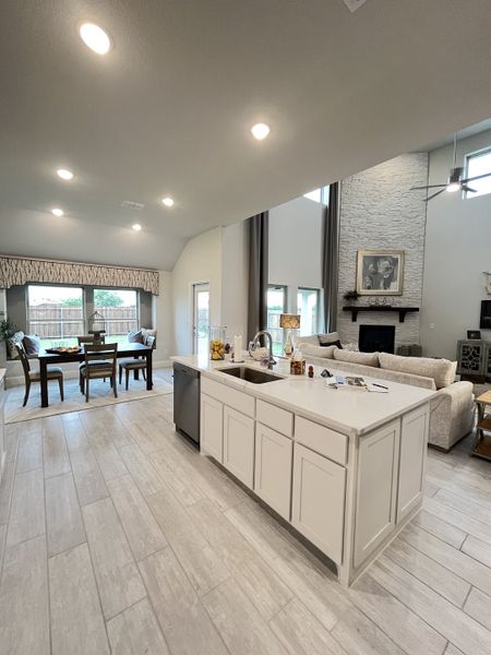 Spacious open-concept living area featuring a sleek kitchen island, elegant dining space, and cozy seating by the fireplace.