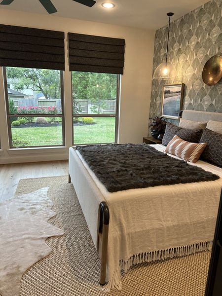 A cozy bedroom featuring patterned wallpaper, large windows, and modern decor for an inviting atmosphere.