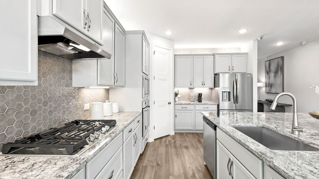 Exquisite white cabinetry, hexagonal backsplash, and luxurious granite countertops define this Green Oaks Preserve kitchen. Exquisite white cabinetry, hexagonal backsplash, and luxurious granite countertops define this Green Oaks Preserve kitchen.