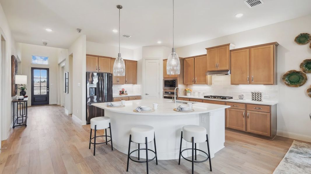 Luxurious kitchen features sleek pendant lighting and exquisite wood cabinetry at The Oaks.
