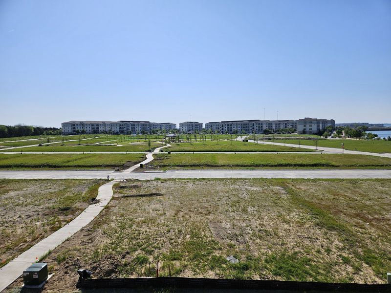 Expansive green spaces with modern, multi-story buildings in Bayside by Beazer Homes (Rowlett, TX).