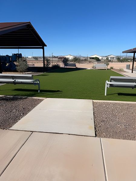 A serene outdoor area with covered seating and manicured green space in North Copper Canyon by Oakwood Homes Co (Surprise, AZ).