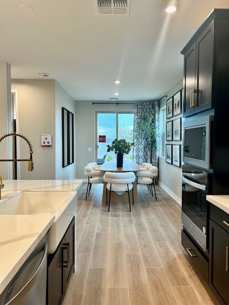A modern kitchen-dining area with sleek cabinetry, wood flooring, and abundant natural light.