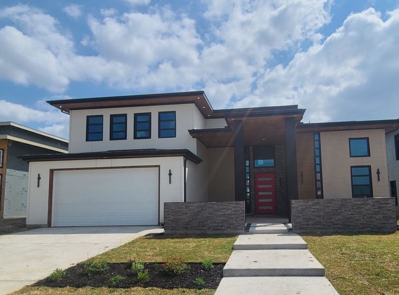 A modern two-story home with a striking red door in The Dawn by NETZE.HOMES (Melissa, TX).