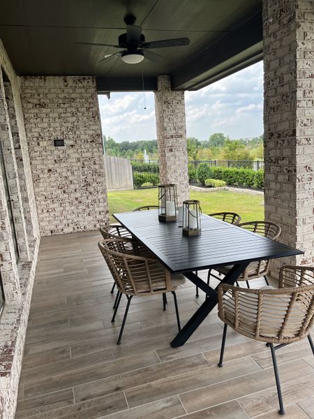 A cozy patio with wicker seating, a sleek black table, and serene views, perfect for outdoor dining and relaxation.
