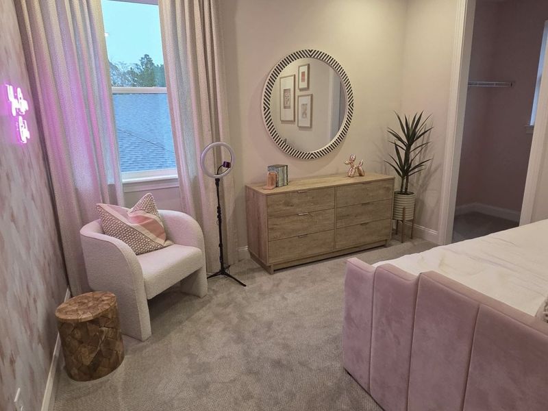 A cozy bedroom with soft carpeting, a chic round mirror, and stylish furniture creating an inviting atmosphere. A cozy bedroom with soft carpeting, a chic round mirror, and stylish furniture creating an inviting atmosphere.