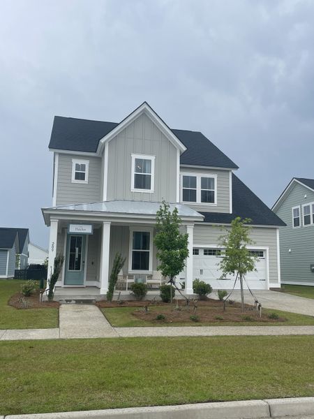 A charming gray home with white trim and a cozy porch in Carnes Crossroads: Coastal Collection by Lennar (Summerville, SC).