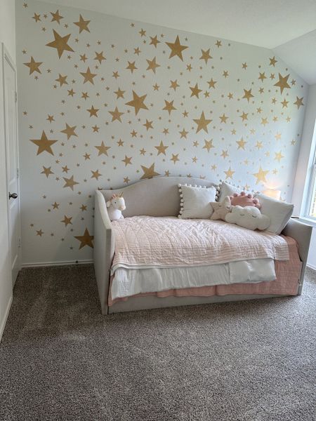 A cozy children's room with star-patterned wallpaper, a soft daybed, and plush toys, perfect for a playful atmosphere.
