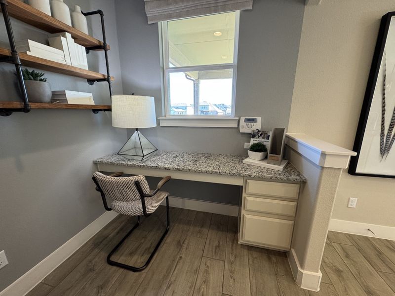 A cozy workspace with a speckled granite desk, sleek chair, modern lamp, and rustic shelves, offering style and functionality.