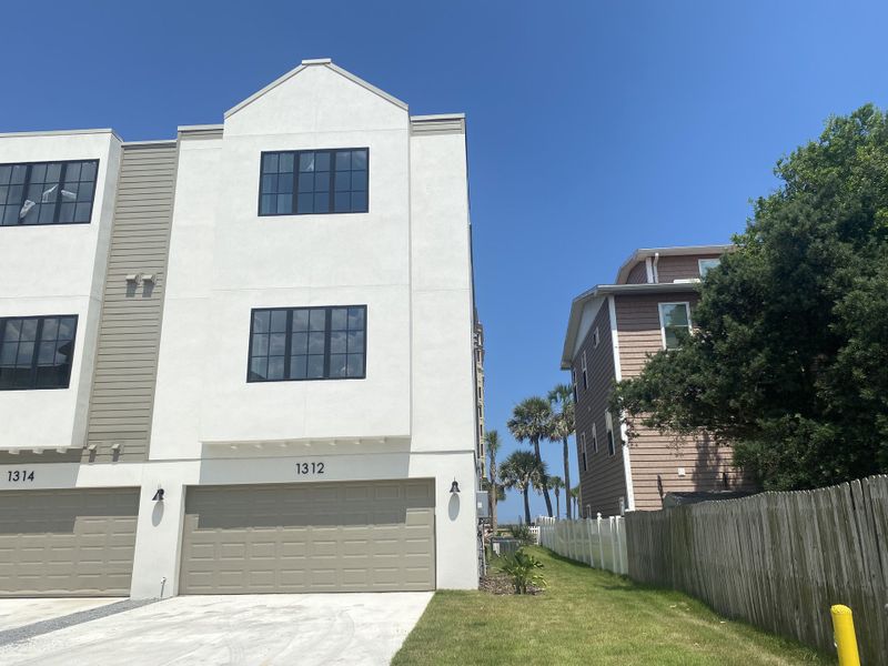 A modern white townhome with large windows and dual garages in Townhomes on 1st by Benchmark Commercial Group (Jacksonville Beach, FL).