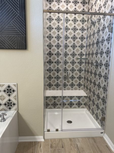 A chic bathroom featuring a tiled shower with geometric patterns, adjacent to a bathtub with matching accents. A chic bathroom featuring a tiled shower with geometric patterns, adjacent to a bathtub with matching accents.