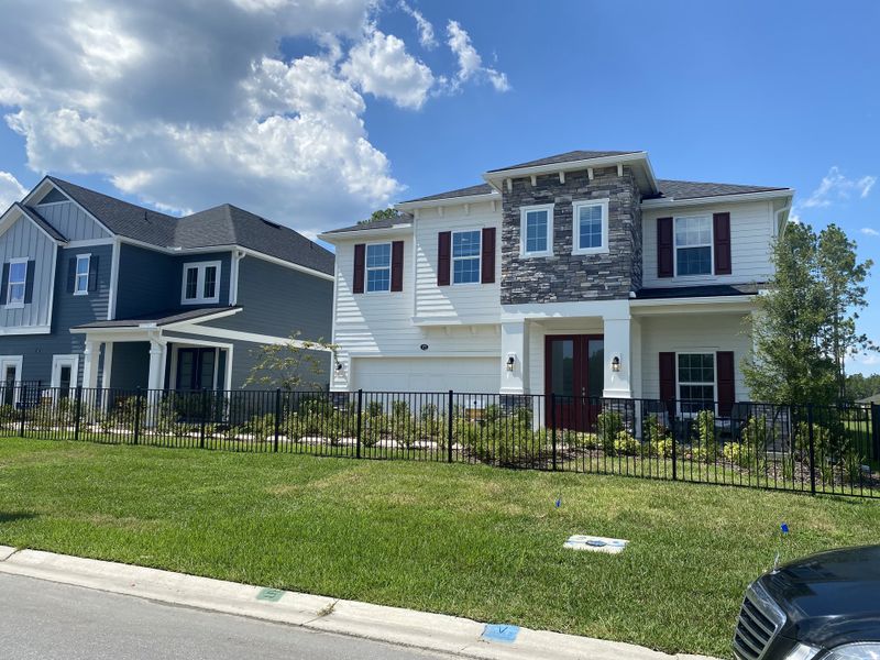 A charming home with stone accents and red shutters in Holly Landing at SilverLeaf by Dream Finders Homes (St. Augustine, FL).