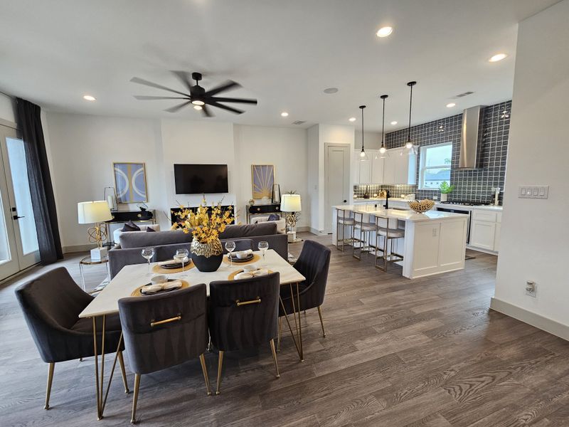 A modern open-concept living area with sleek kitchen, stylish dining space, and contemporary decor, featuring dark wood flooring.