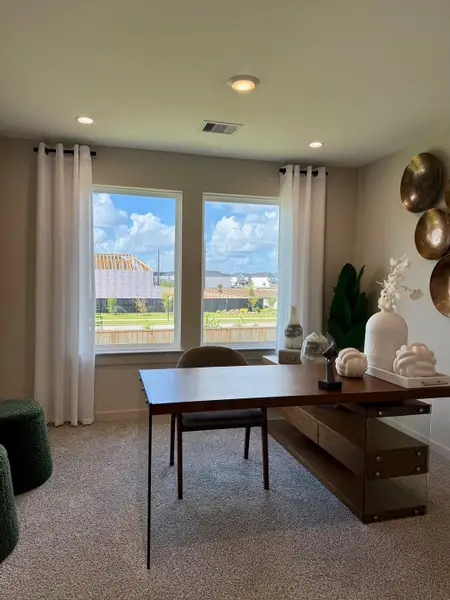 A contemporary home office with a sleek wooden desk, elegant decor, and large windows offering natural light and outdoor views.