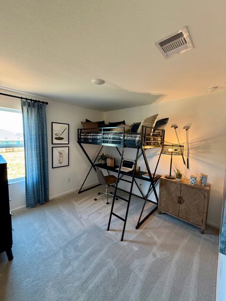 A cozy bedroom with a loft bed, study desk underneath, and stylish decor. Ample natural light flows through a large window.