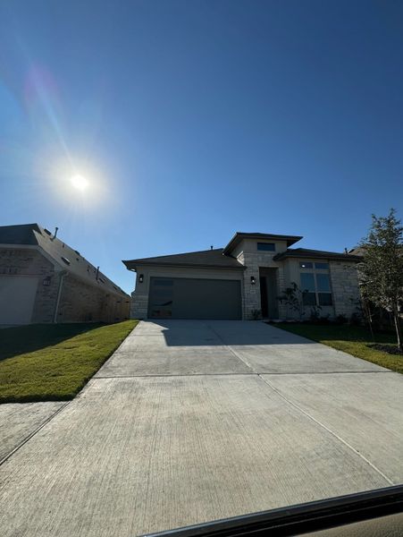 A modern stone-accented home with a spacious driveway in Sunfield by Brightland Homes (Buda, TX). A modern stone-accented home with a spacious driveway in Sunfield by Brightland Homes (Buda, TX).