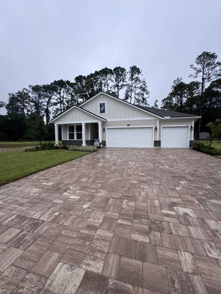 A modern white home with a charming porch and three-car garage in Creighton Pointe by Drees Custom Homes (Fleming Island, FL).
