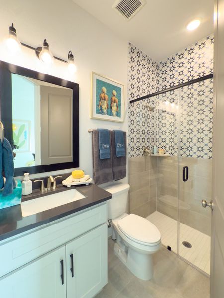 A modern bathroom featuring a glass shower with patterned tiles, sleek vanity, and stylish lighting. A modern bathroom featuring a glass shower with patterned tiles, sleek vanity, and stylish lighting.