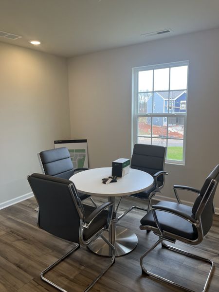 A chic meeting room with a round table, sleek black chairs, and natural light streaming through the window. A chic meeting room with a round table, sleek black chairs, and natural light streaming through the window.