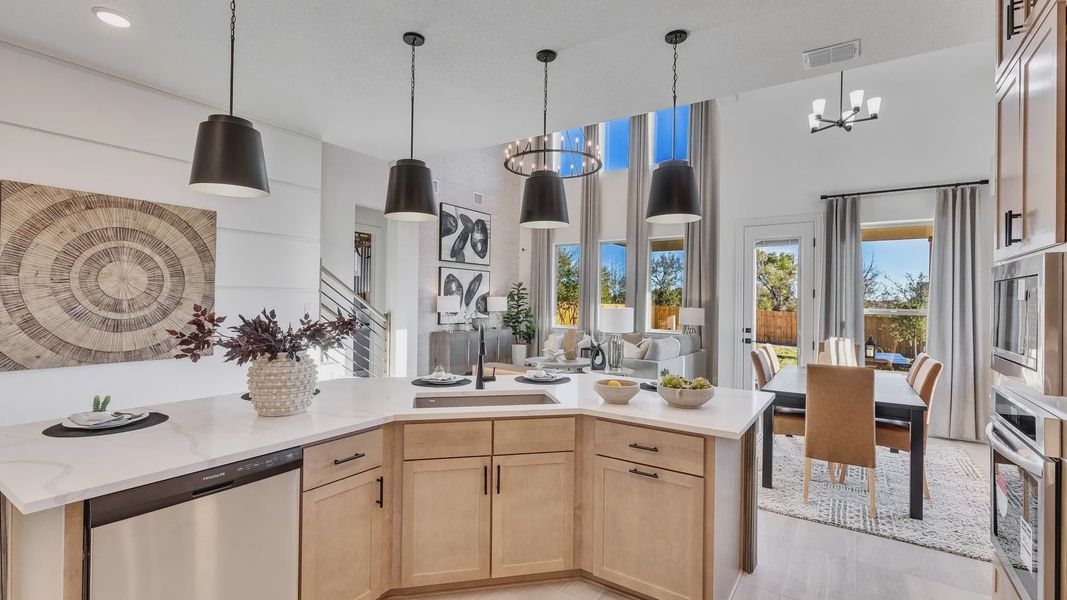 Step into luxury with this open kitchen and dining space, featuring chic pendant lighting and elegant wood finishes in Creeks Crossing.