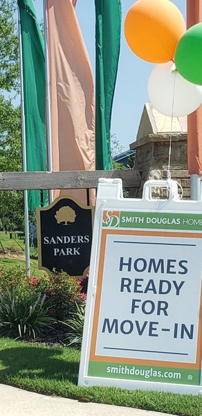 A vibrant signage in Sanders Park by Smith Douglas Homes, Austell GA, promotes ready-to-move-in homes amid lush landscaping. A vibrant signage in Sanders Park by Smith Douglas Homes, Austell GA, promotes ready-to-move-in homes amid lush landscaping.