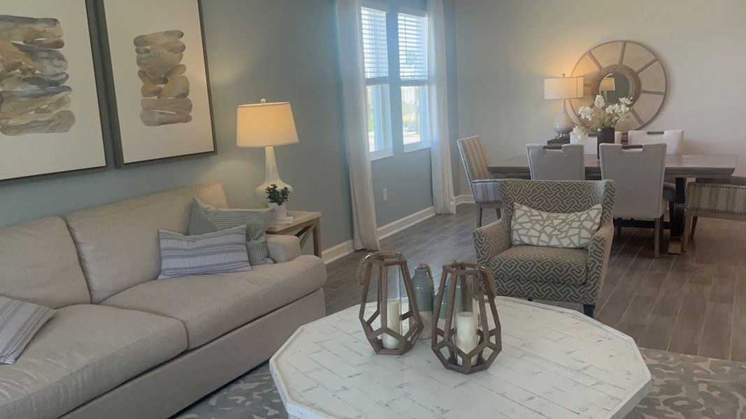 A cozy living space with soft blue walls, light furniture, patterned accents, and elegant lighting.