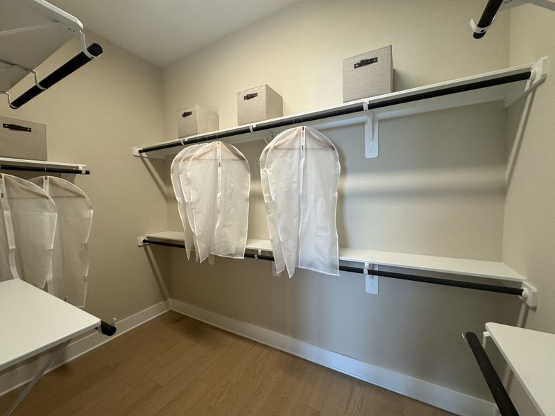 A spacious walk-in closet with sleek shelving, garment bags, and storage boxes for organized, efficient storage.