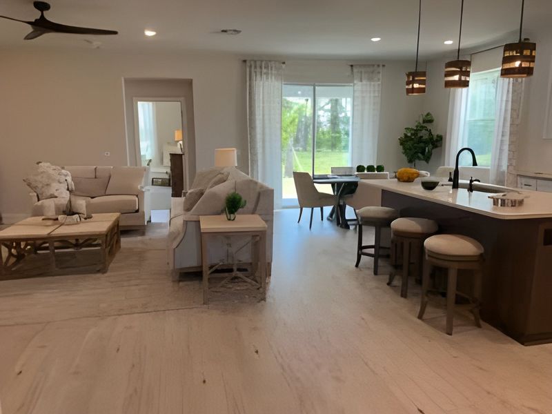 A modern open-concept living space with neutral tones, cozy seating, a sleek kitchen island, and large sliding glass doors.