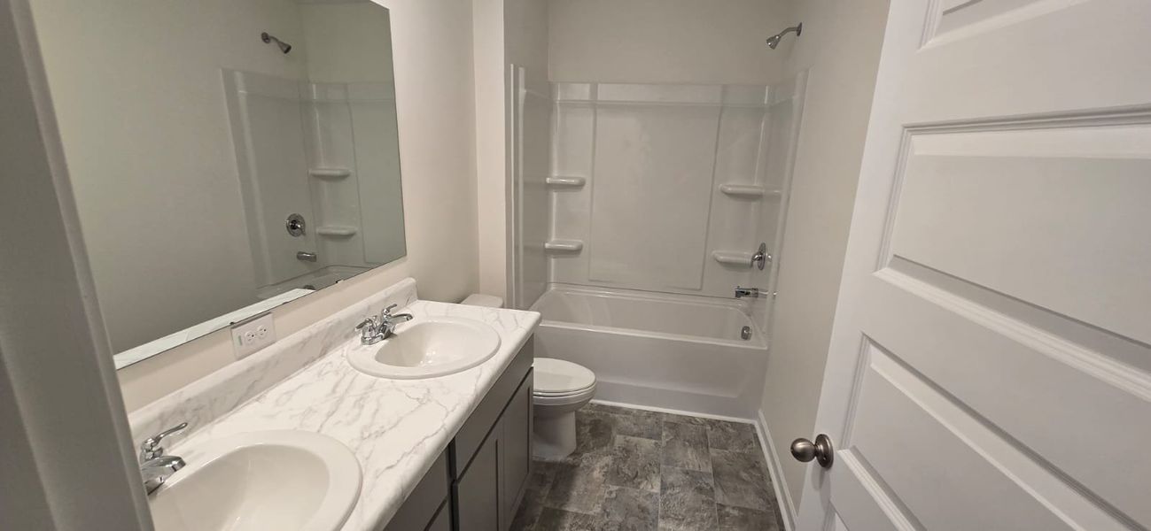 A modern bathroom with dual sinks, marble countertops, and a spacious shower-tub combo.