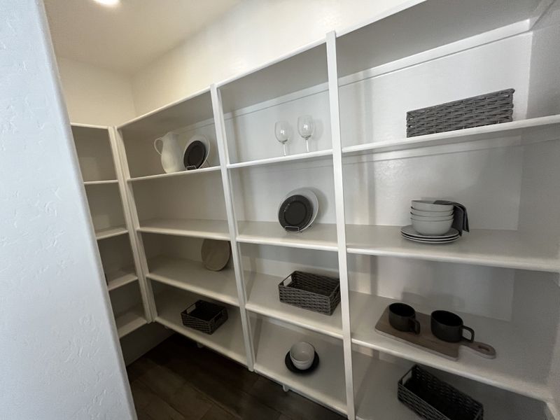 Large pantry with white shelving, organized storage baskets, and neatly arranged dishes.