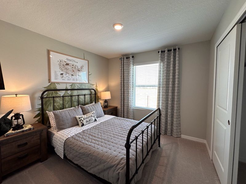 A cozy bedroom featuring a metal bed, forest-themed decor, and soft lighting, creating a tranquil retreat.