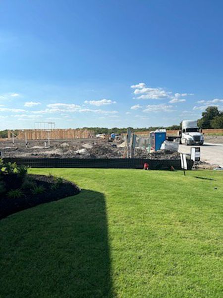 Construction site with lush green lawn and blue skies in Hillstead 60' by Perry Homes (Lavon, TX).