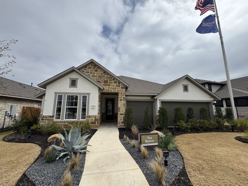 A charming stone-brick home with manicured landscaping in Meyer Ranch by David Weekley Homes (New Braunfels, TX).