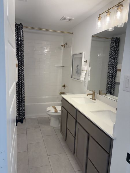 A sleek bathroom featuring a double vanity, modern fixtures, and a stylish patterned shower curtain.